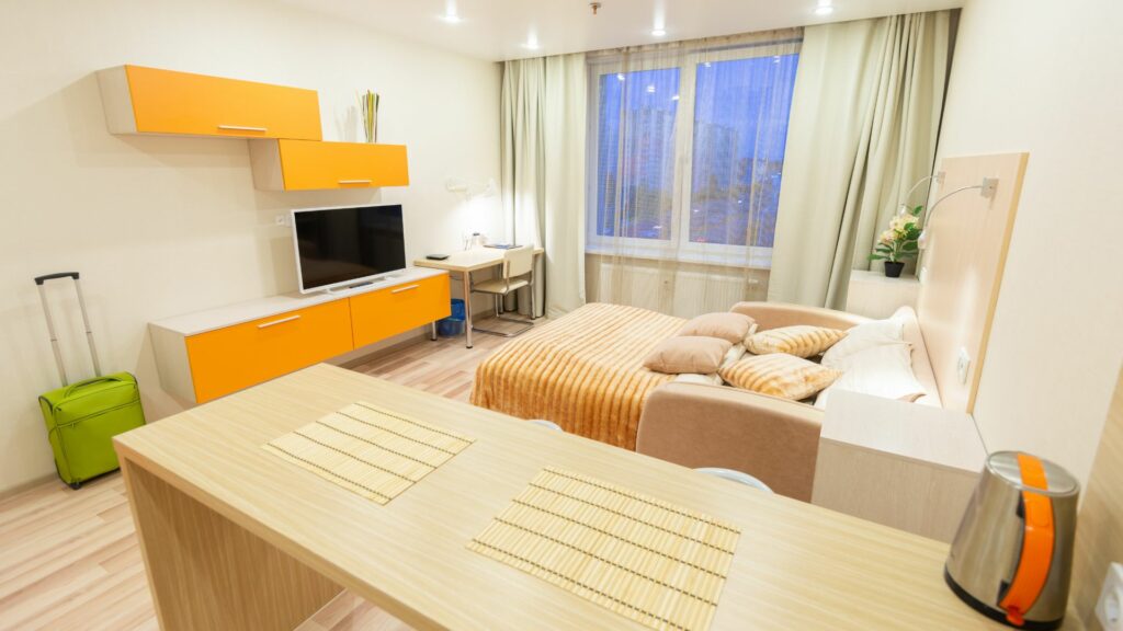 Une chambre d'étudiant lumineuse et bien meublée avec un lit, un bureau et une étagère, dans une résidence étudiante.